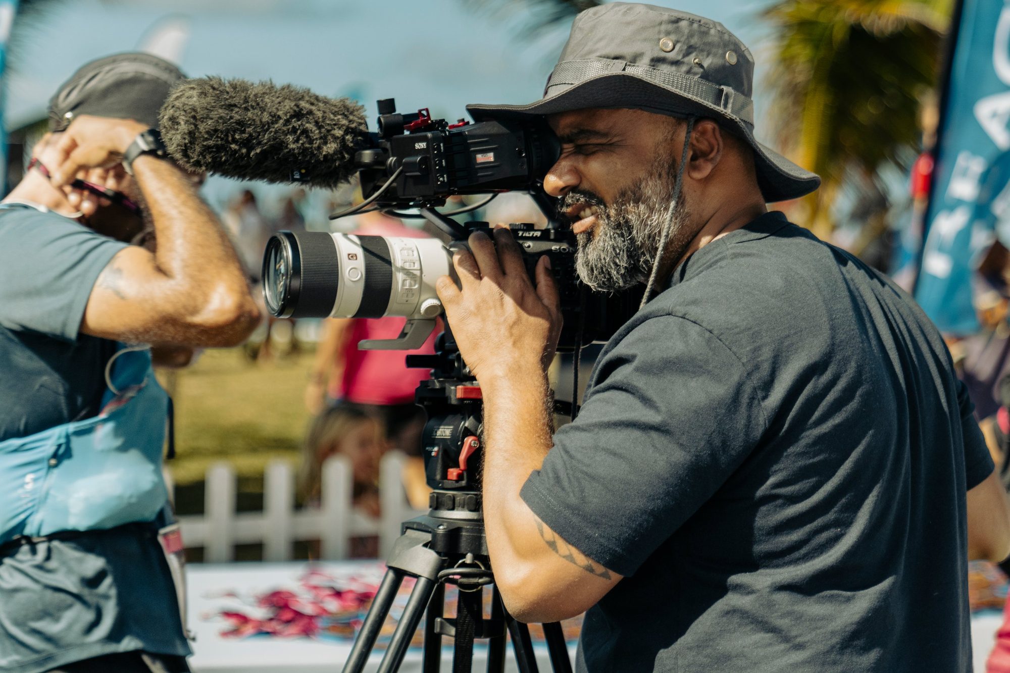 Arvind Mattadeen operating a camera with a shotgun microphone at an outdoor event