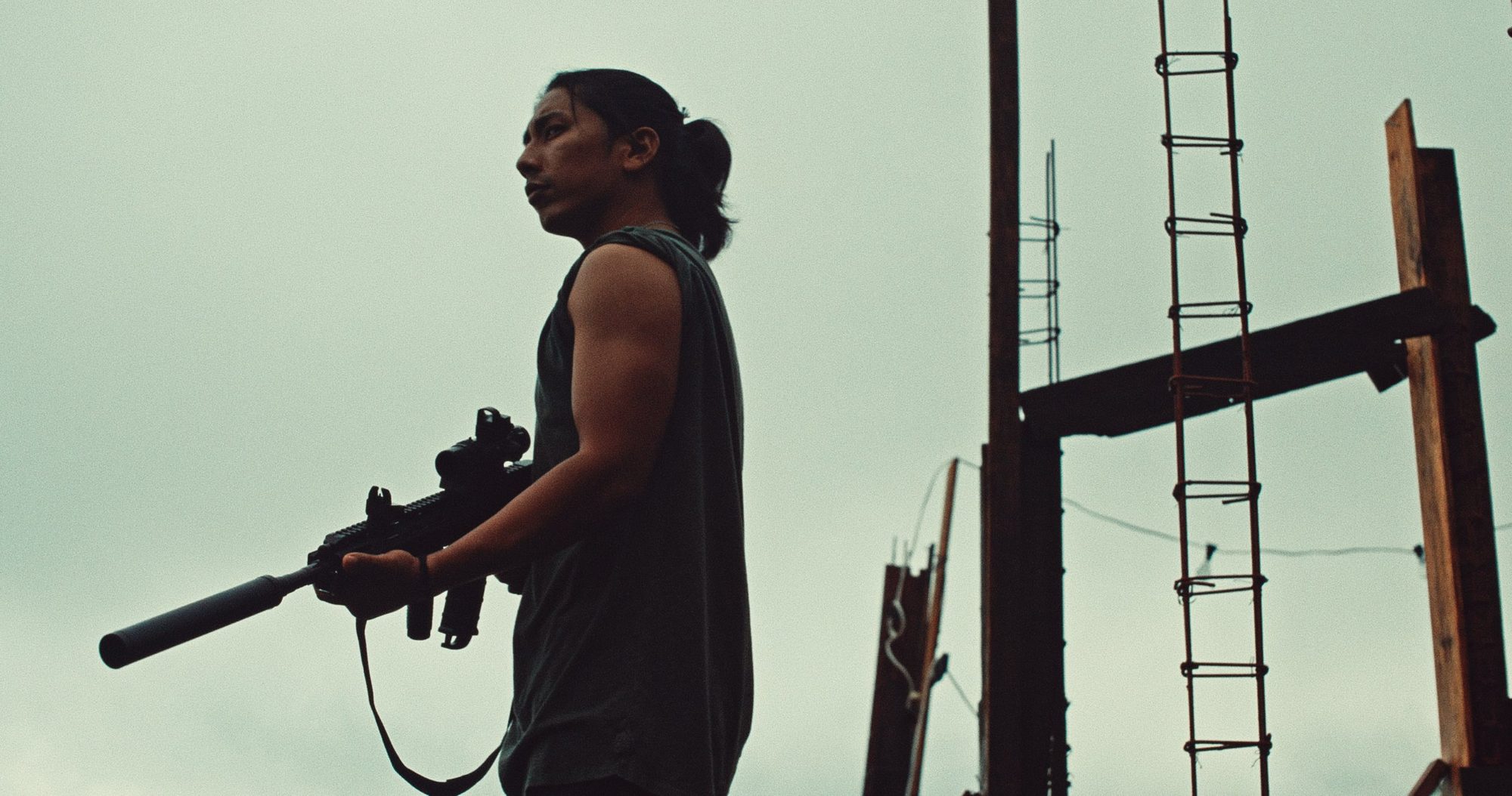 A man with a rifle in silhouette against a pale sky
