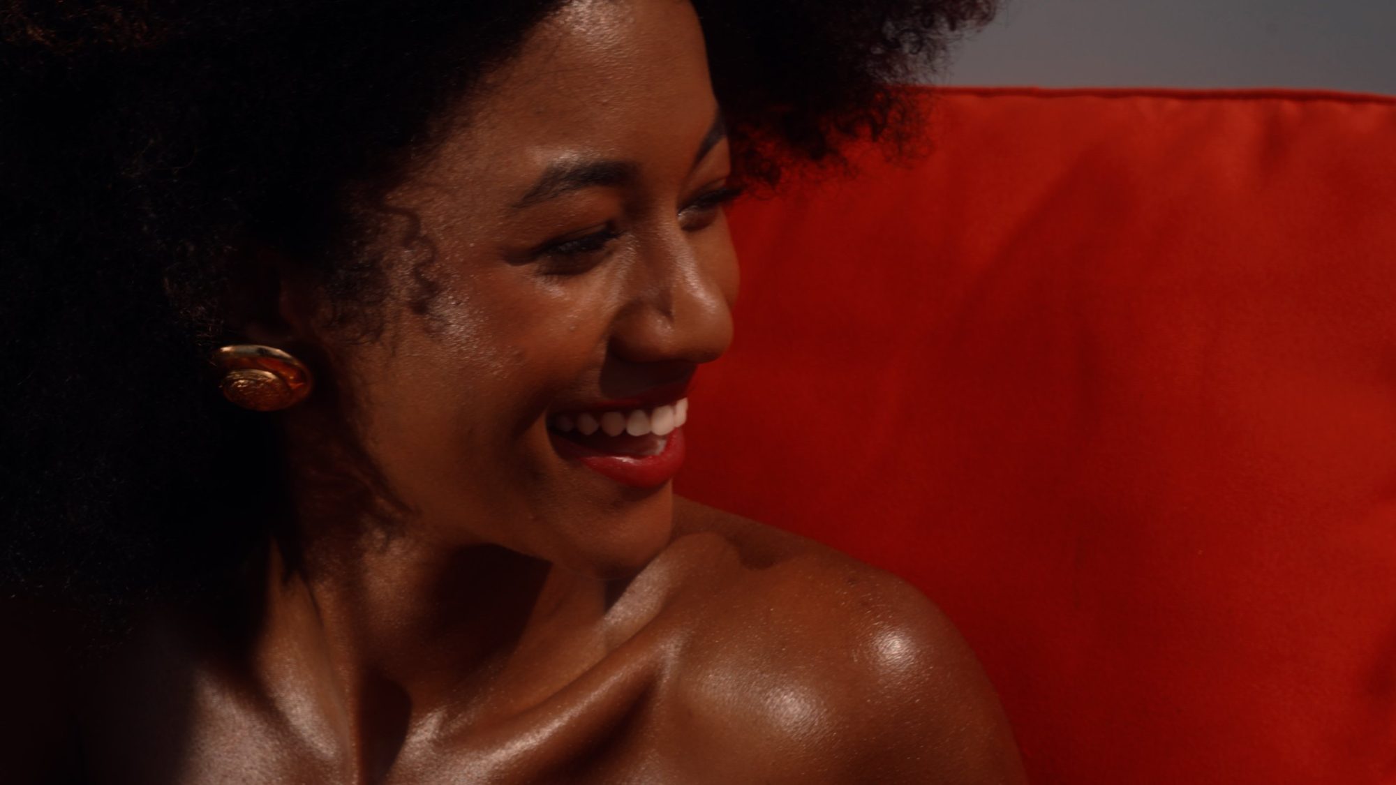 A woman laughs against an orange cushion